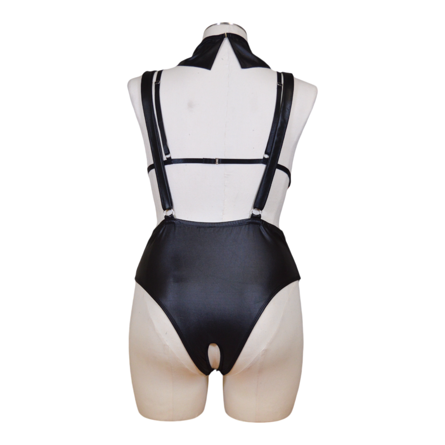 A mannequin displaying a plaid bralette, black suspender bodysuit, and a red necktie.