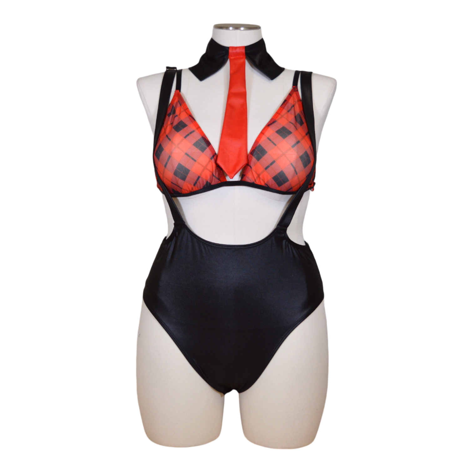 A mannequin displaying a plaid bralette, black suspender bodysuit, and a red necktie, arranged as a set of lingerie.