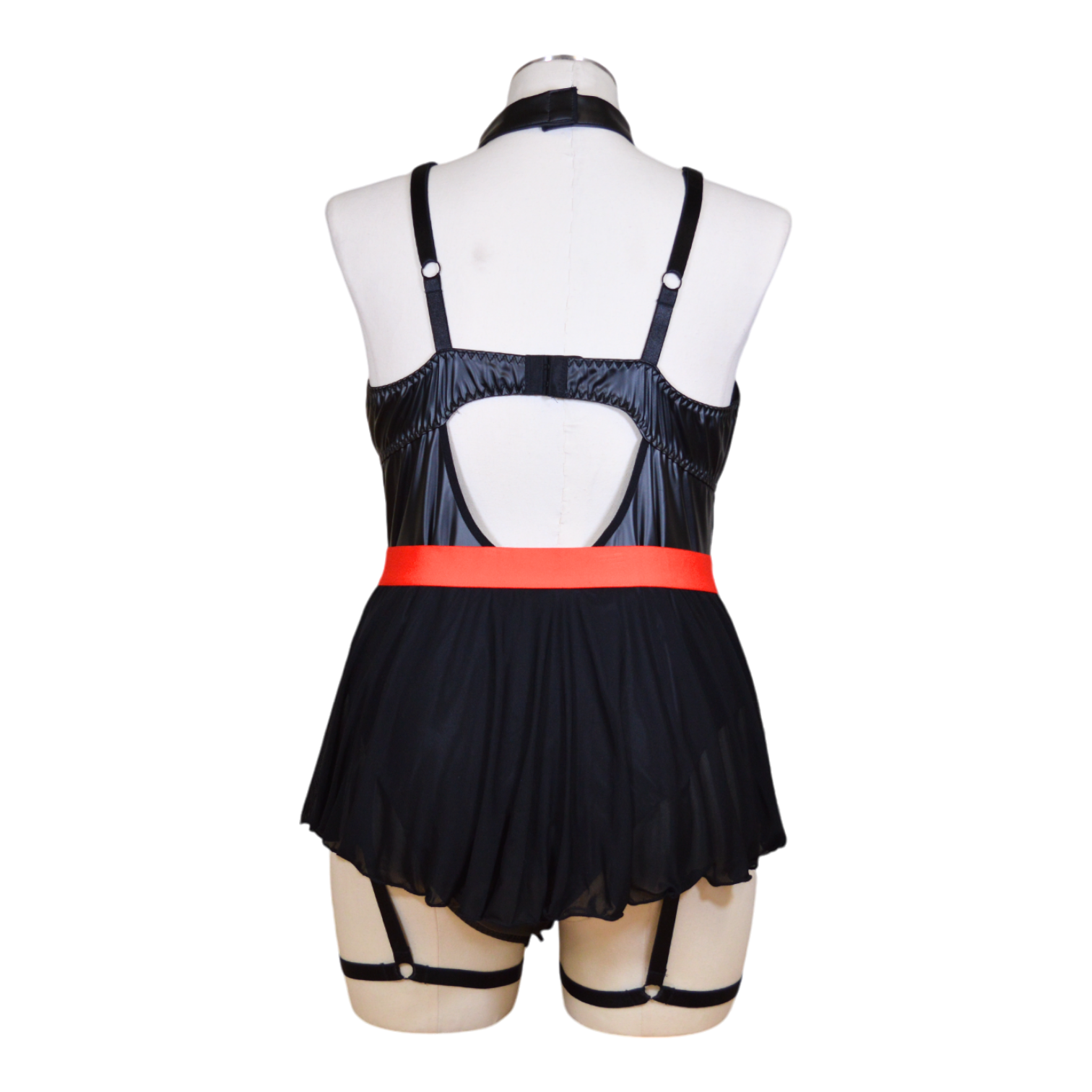 A black leather nurse costume displayed on a mannequin, featuring a revealing neckline, a red belt, and garter straps. Accessories including a choker and hat are also visible.