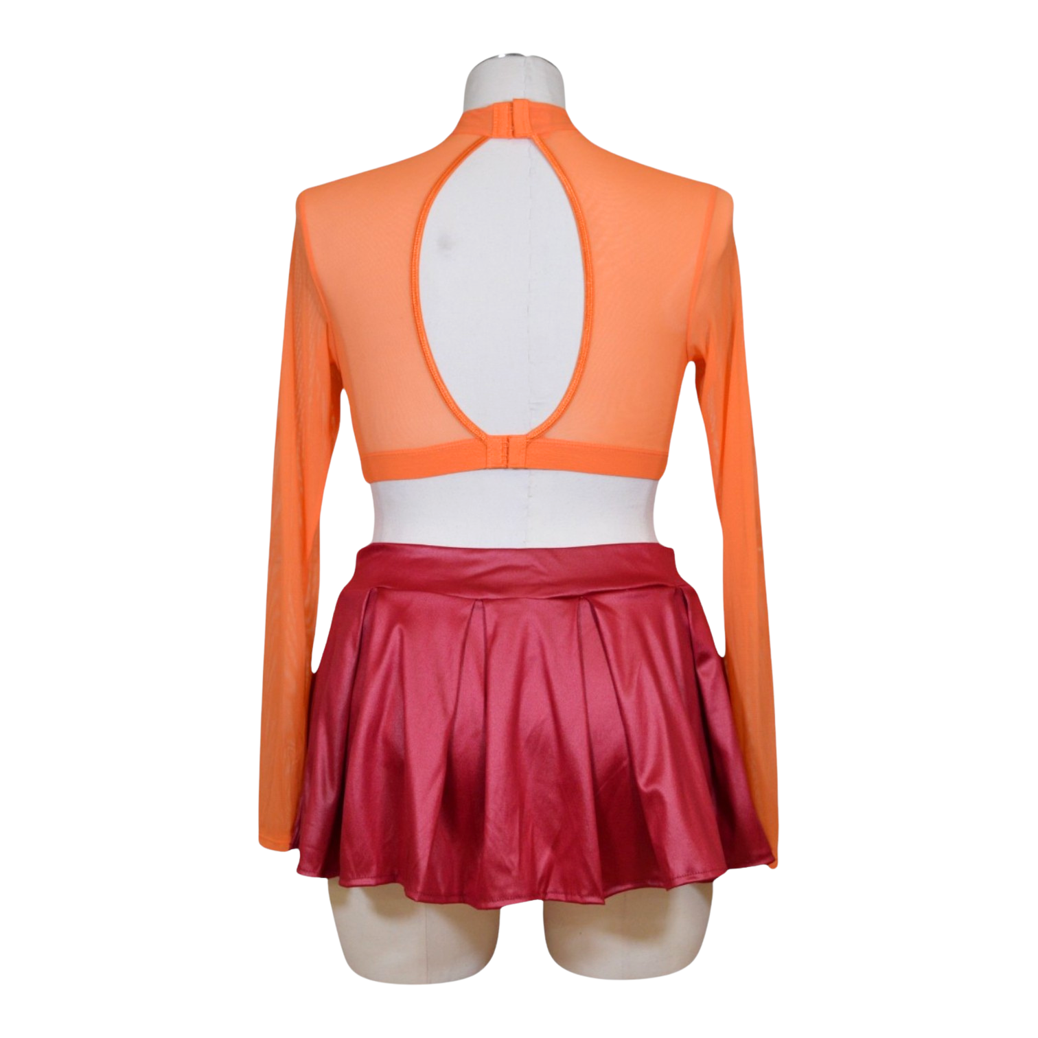 An orange long sleeve crop top with floral cut-outs and a keyhole back, paired with a red pleated mini skirt. Accessories including pasties are included back view.