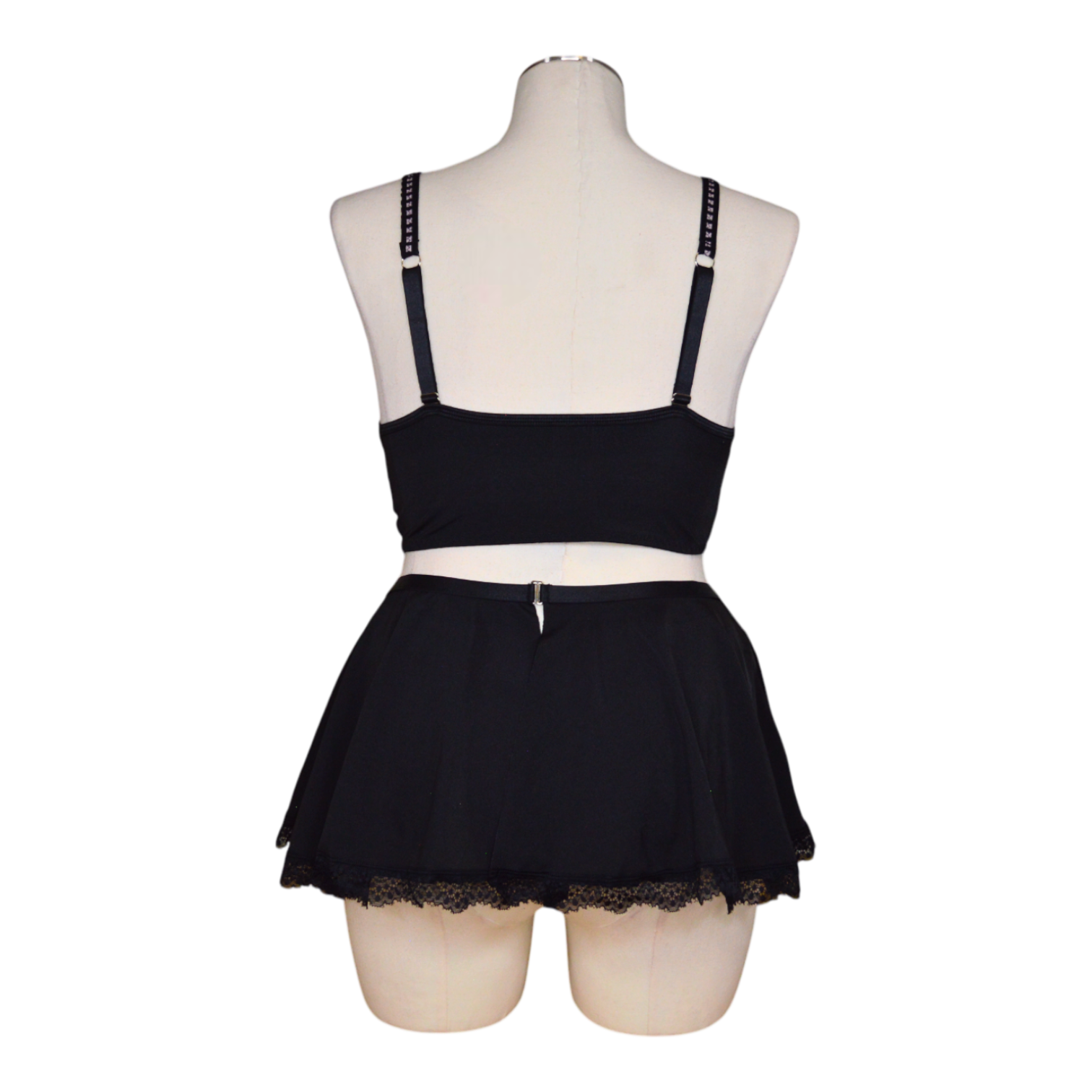 A black lingerie set with pink accents, featuring garter straps and lace detailing, displayed on a mannequin.