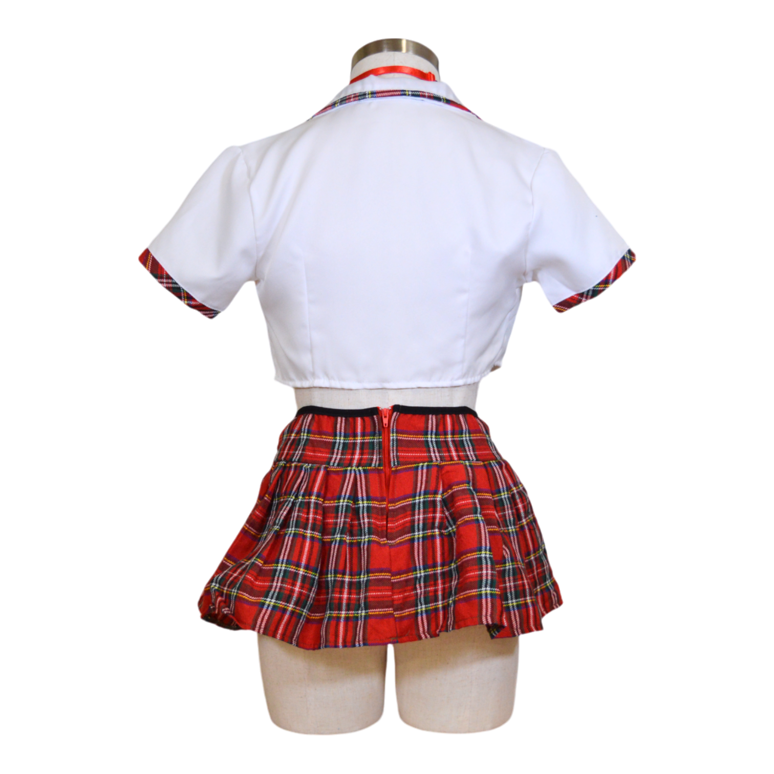 A mannequin wearing a white cropped top with a tie front and attached collar, and a matching plaid mini skirt with a plaid tie back.