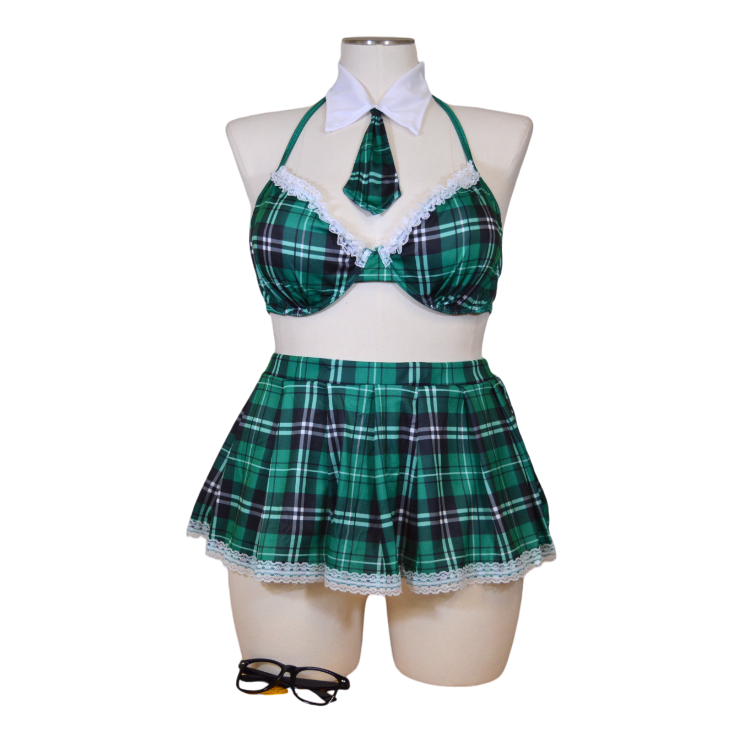 A mannequin wearing a green plaid schoolgirl costume set which includes a bra top, a skirt, and glasses.