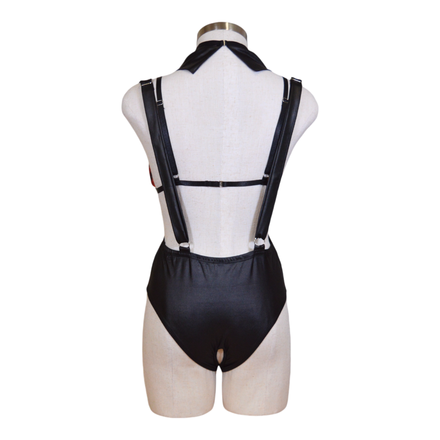 A mannequin displaying a plaid bralette, black suspender bodysuit, and a red necktie.