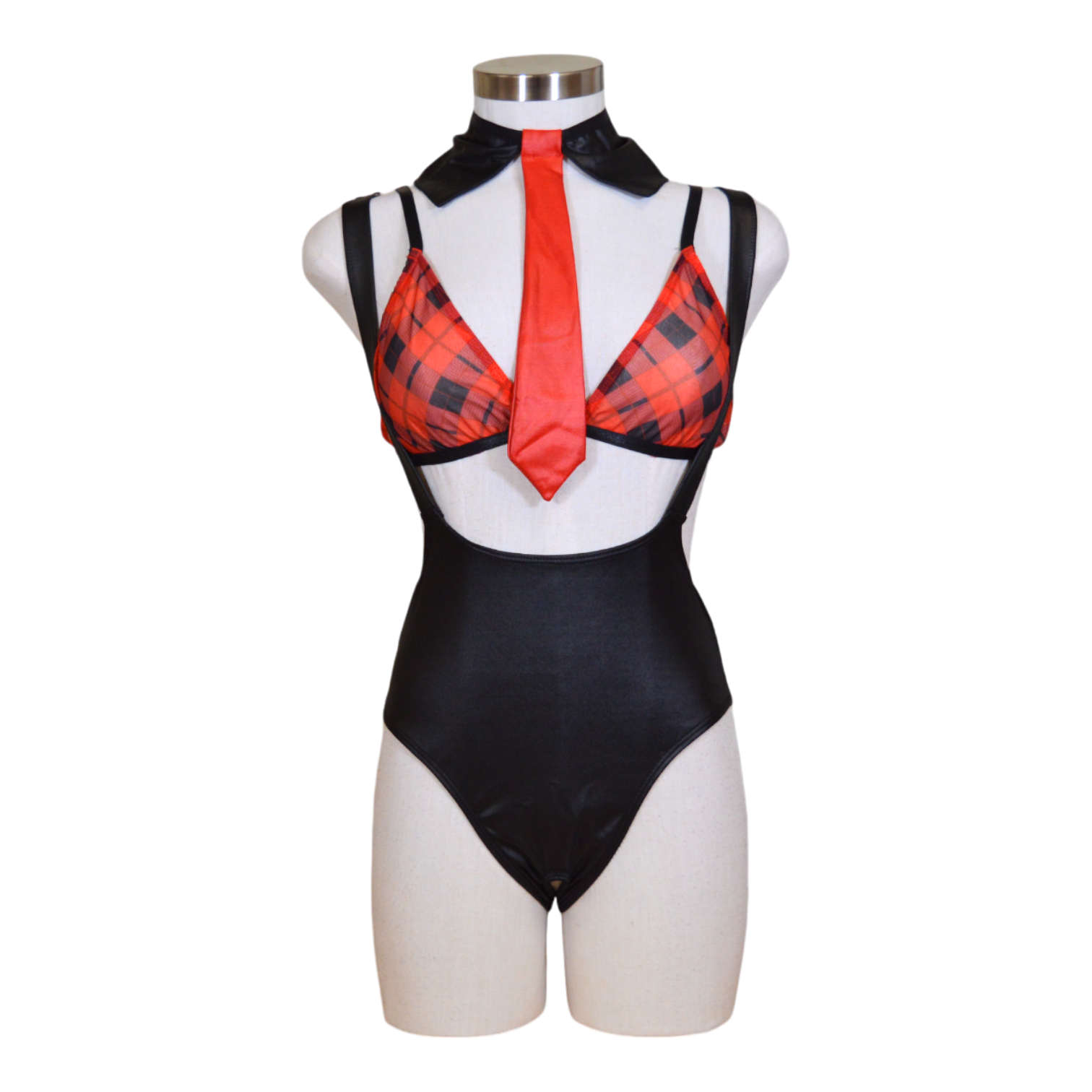 A mannequin displaying a plaid bralette, black suspender bodysuit, and a red necktie.