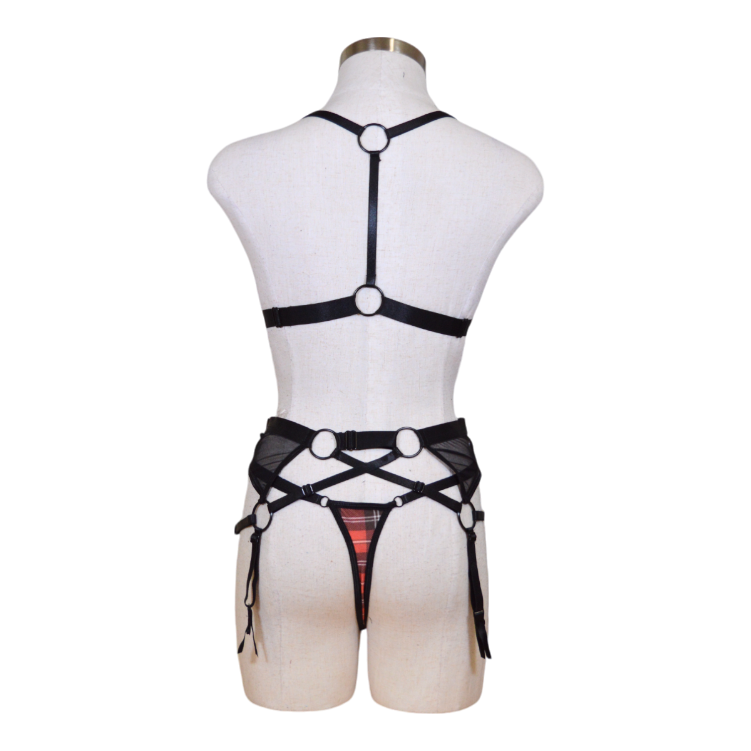 This image features a seductive 3-piece lingerie set displayed on a mannequin, highlighting a bold red and black plaid pattern. The set includes a strikingly designed bra with adjustable straps and mesh accents, a matching garter belt with similar plaid and mesh detailing, and coordinating panties that complement the bra and garter belt back view.